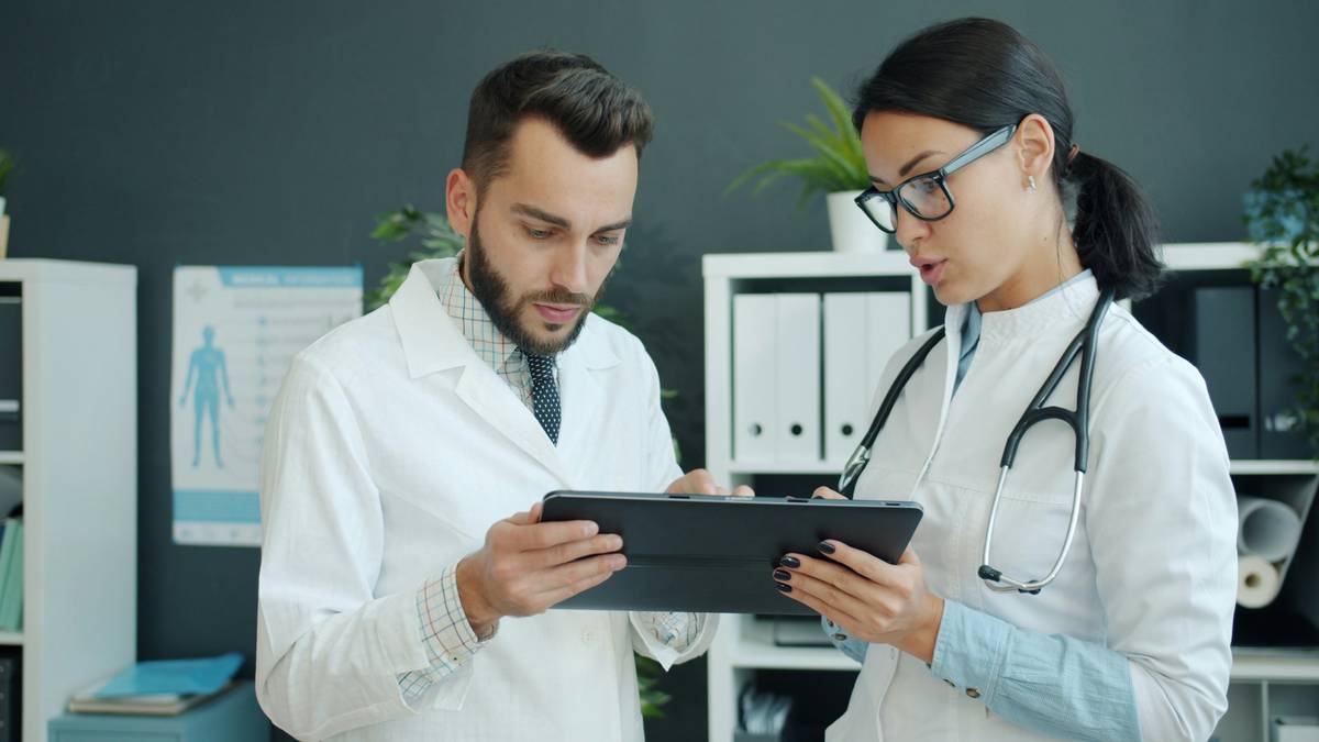 A diverse team of healthcare professionals collaborating around digital health dashboard screens, representing administrative careers in healthcare